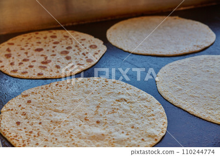 Freshly Baked Tortillas on Dark Cooking Surface in Warm Indoor Lighting Freshly Baked Tortillas on Dark Cooking Surface in Warm Indoor Lighting 110244774