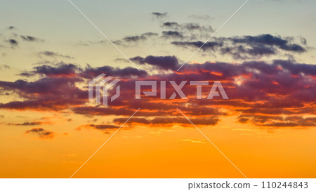 Inspirational orange sky with glorious pink and purple clouds in dreamy setting 110244843