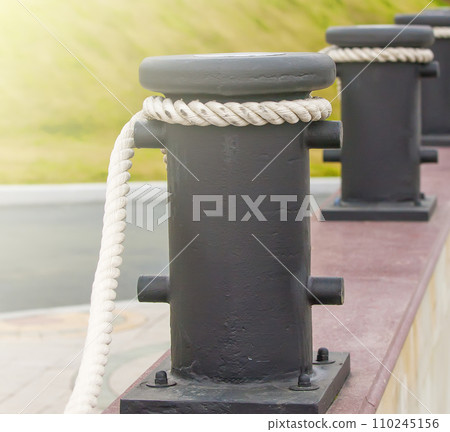 Bollards with ropes on a quay for decorative fencing. 110245156