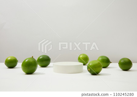 Plump green lemons stand out on a white background with a round platform placed in the center of the frame. Lemon is an effective skin beautifying food, treating acne and dark scars. Plump green lemons stand out on a white background with a round platform placed in the center of the frame. Lemon is an effective skin beautifying food, treating acne and dark scars. 110245280