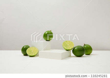 Vibrant green lemons pop against a white backdrop with a centered podium. A potent skin-beautifying food, lemons effectively address acne and dark scars. Vibrant green lemons pop against a white backdrop with a centered podium. A potent skin-beautifying food, lemons effectively address acne and dark scars. 110245281