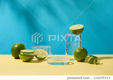 Cylindrical glass platforms are placed next to fresh lemons on a blue background. Space viewed from the front for product display. Copy space for ads. 110245313