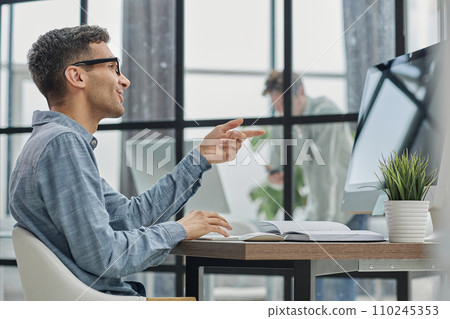 man working on a laptop at a desk, photo in profile man working on a laptop at a desk, photo in profile 110245353