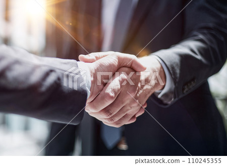 executives shaking hands in front of their manager and a colleague 110245355