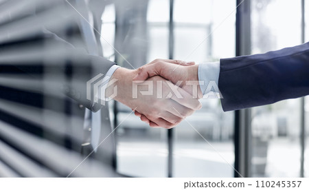 executives shaking hands in front of their manager and a colleague executives shaking hands in front of their manager and a colleague 110245357