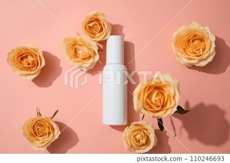 Top view of an unlabeled bottle on pink background with fresh roses. Rose extract Vitamin C shields skin from UV rays, preventing aging. Cosmetic concept. Top view of an unlabeled bottle on pink background with fresh roses. Rose extract Vitamin C shields skin from UV rays, preventing aging. Cosmetic concept. 110246693