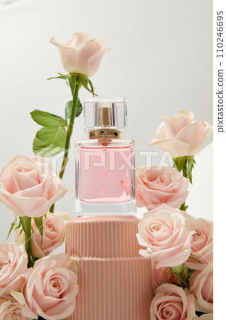 Close-up of an unlabeled perfume bottle displayed on a podium with fresh roses decorated around it. Roses are commonly used in the perfume industry. Close-up of an unlabeled perfume bottle displayed on a podium with fresh roses decorated around it. Roses are commonly used in the perfume industry. 110246695