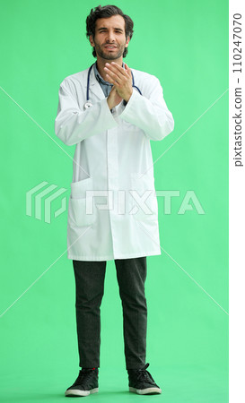 male doctor in a white coat on a green background applauds 110247070
