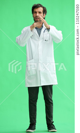 male doctor in a white coat on a green background shows a sign take a break 110247080