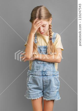 A worried little girl holds her head. A worried little girl holds her head. 110247543