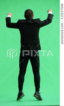 man in full growth. isolated on green background jumping rejoices. back view 110247986