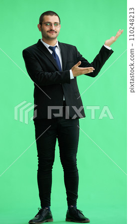 young man in full growth. isolated on green background demonstrates with hands young man in full growth. isolated on green background demonstrates with hands 110248213