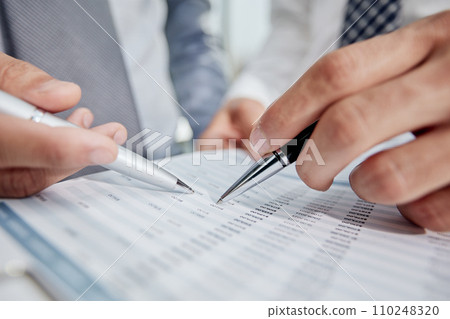 An office worker in a white shirt looks at the financial report. Close-up An office worker in a white shirt looks at the financial report. Close-up 110248320