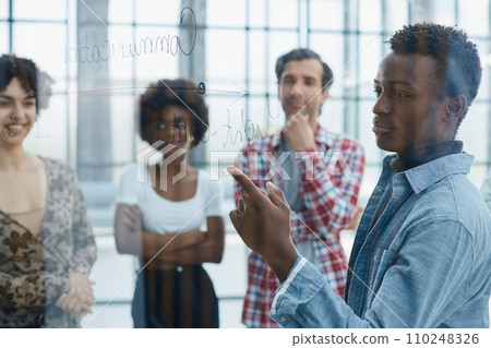 a team of young designers sticking notes on glass in a modern office 110248326