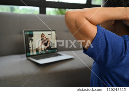 Active senior woman watching video training tutorial online and doing stretching exercises at home. Active senior woman watching video training tutorial online and doing stretching exercises at home. 110248815