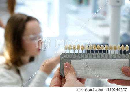 video tooth whitening, perfect white crown teeth close up with shade guide bleach color, female veneer smile, dental care and stomatology, dentistry, copyspace. 110249557