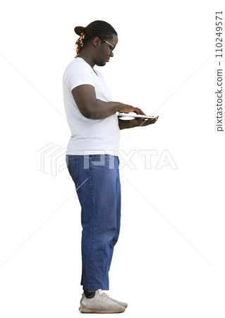 Full-length man in a white T-shirt typing on a laptop on a White background, in profile Full-length man in a white T-shirt typing on a laptop on a White background, in profile 110249571