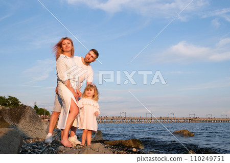 young happy family with the child at sunset at water look afar young happy family with the child at sunset at water look afar 110249751