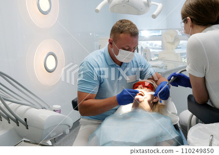Female dentists treat teeth to a patient in a medical office. 110249850