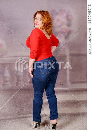 Woman with red jacket standing on bakground woman turned her back to the camera big puffy breasts and ass redhead beauty in high heels 110249948