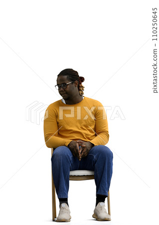 a man in a yellow sweater on a White background sits on a chair and looks to the side 110250645