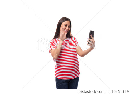 young smiling stylish european brunette woman dressed in striped clothes chatting on the phone on a 110251319