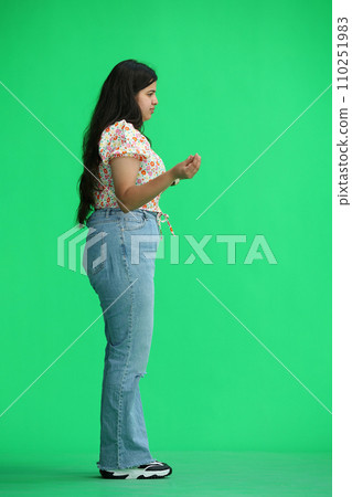 A woman, on a green background, in full height, profile 110251983