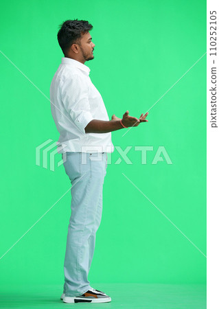 A man in a white shirt, on a green background, in full height, spreads his arms, profile A man in a white shirt, on a green background, in full height, spreads his arms, profile 110252105