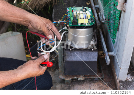 Hands of an electrician with multimeter probe at electric board panel. 110252194