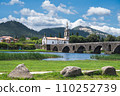 Bridge across the river in Ponte de Lima, southern bank, medieval bridge dates back to 1368, view of the church, river back, mountains or hills on the background, selective focus 110252739