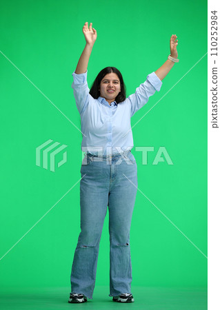 A girl in a blue shirt, on a green background, in full height, waving her arms 110252984