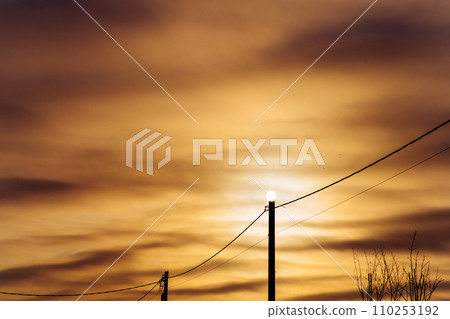 Sun on an electric pole before sunset. Concept of lack of electricity, energy crisis. Mystical sunset on a frosty winter evening. Sun on an electric pole before sunset. Concept of lack of electricity, energy crisis. Mystical sunset on a frosty winter evening. 110253192