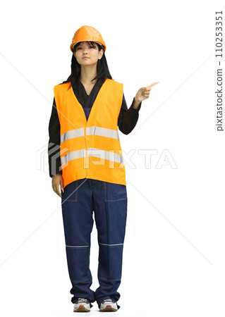 A construction worker girl, on a white background, in full height, points to the side 110253351
