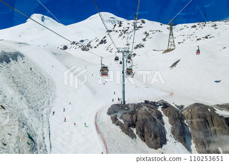Cabin ski lift gondola against snow mountain peaks covered in snow landscape in winter resort. Winter leisure sports, recreation and travel Cabin ski lift gondola against snow mountain peaks covered in snow landscape in winter resort. Winter leisure sports, recreation and travel 110253651