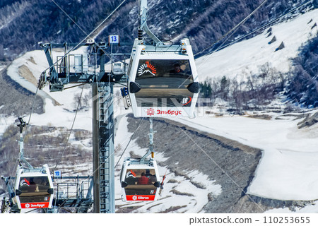 Cabin ski lift gondola against snow capped forest tree and mountain peaks covered in snow landscape in winter resort. Winter leisure sports, recreation and travel Cabin ski lift gondola against snow capped forest tree and mountain peaks covered in snow landscape in winter resort. Winter leisure sports, recreation and travel 110253655