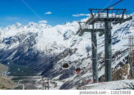 Cabin ski lift gondola against snow capped forest tree and mountain peaks covered in snow landscape in winter resort. Winter leisure sports, recreation and travel Cabin ski lift gondola against snow capped forest tree and mountain peaks covered in snow landscape in winter resort. Winter leisure sports, recreation and travel 110253688