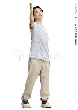A guy in a gray T-shirt, on a white background, standing tall, waving to the side A guy in a gray T-shirt, on a white background, standing tall, waving to the side 110253924