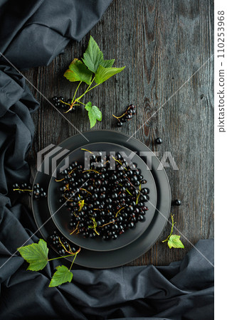 Black currant with leaves on a old wooden table. Black currant with leaves on a old wooden table. 110253968