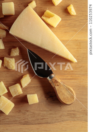 Parmesan cheese with knife on a wooden background. Parmesan cheese with knife on a wooden background. 110253974