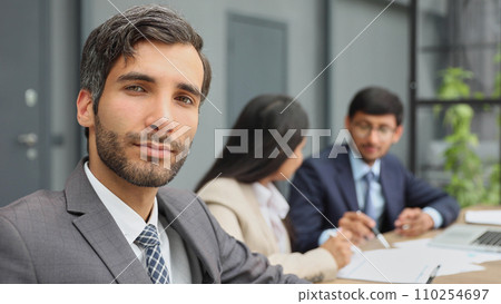 male boss against the background of her colleagues looks at the camera in a modern office 110254697