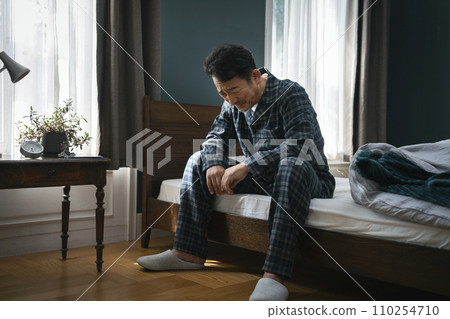 Middle-aged man sitting on bed and feeling depressed 110254710