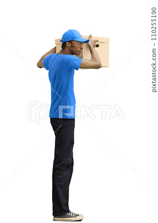 A male deliveryman, on a white background, full-length, with a box, shakes the box 110255190