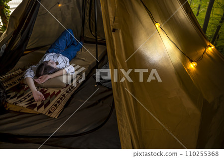 在室內露營地的帳篷裡放鬆的年輕女子 110255368
