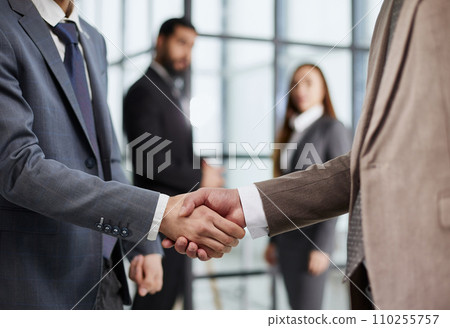 close-up of a handshake of business partners against the background of colleagues close-up of a handshake of business partners against the background of colleagues 110255757