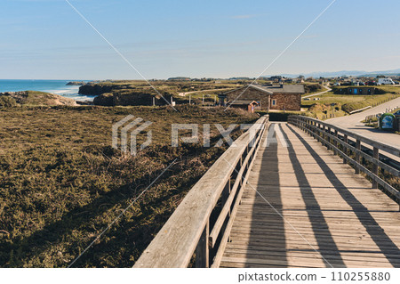 Wooden pedestrian boardwalk leading along beach. Spain 110255880
