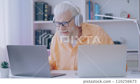 Excited senior man plays a video game on his laptop at home, embracing it as a retirement hobby 110256673