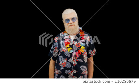 Positive mature man in a Hawaiian shirt stands against a black background, radiating happiness like a joyful tourist Positive mature man in a Hawaiian shirt stands against a black background, radiating happiness like a joyful tourist 110256679