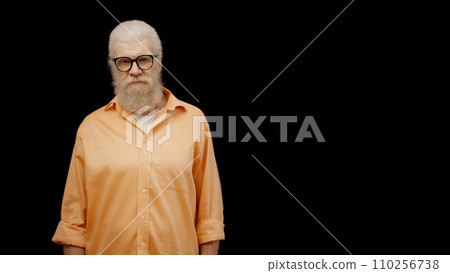 A displeased senior man standing against a black background, providing space for your text 110256738