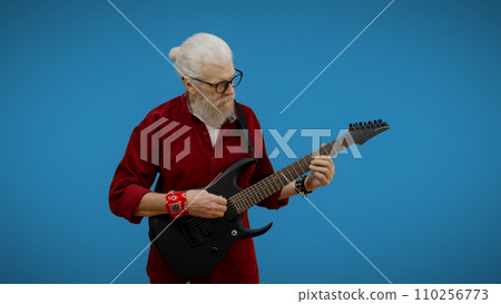 Mature man plays the guitar against a blue background, channeling rock and roll as a senior rockstar 110256773