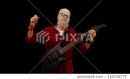Modern mature man enjoys playing the electric guitar against a black background, living his rockstar dream 110256775